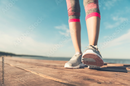 Legs in sneakers close-up. Health and Yoga Concept. Rear view close up strong athletic female legs and running shoes of sport. Sporty young girl practicing yoga. Woman do gymnastics outdoors