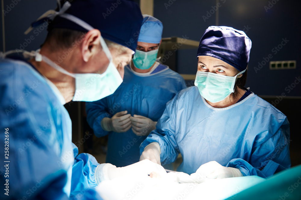 Team of surgeons working together during operation in darkness Team of surgeons working together during operation in darkness