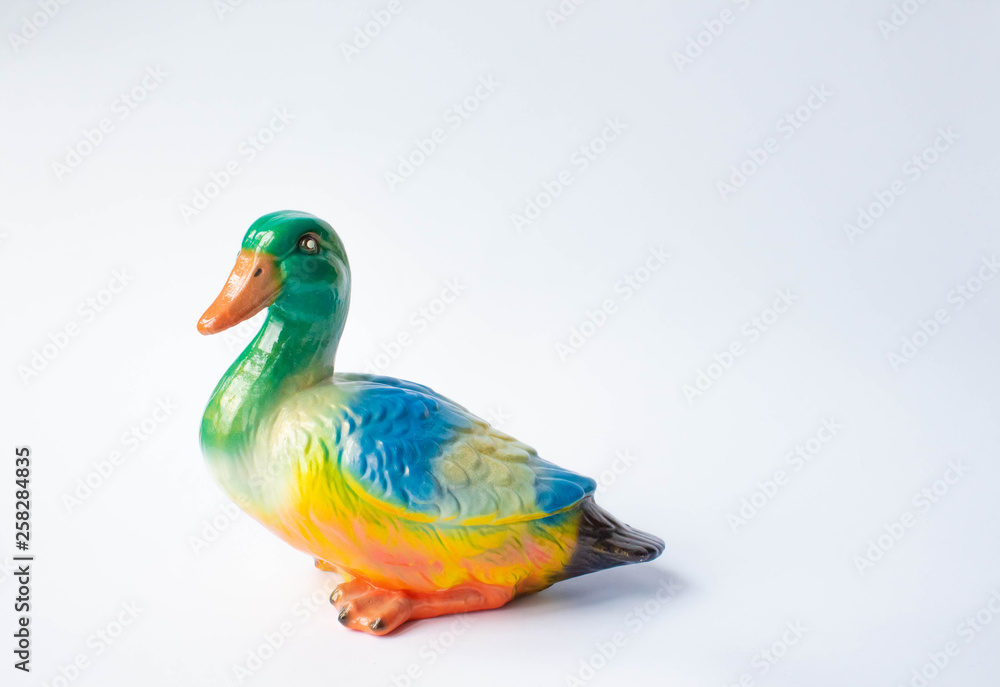 Ceramic statuette of a duck on a white background with brightly colored feathers. Duckling with mother duck Ceramic statuette of a duck on a white background with brightly colored feathers. Duckling with mother duck