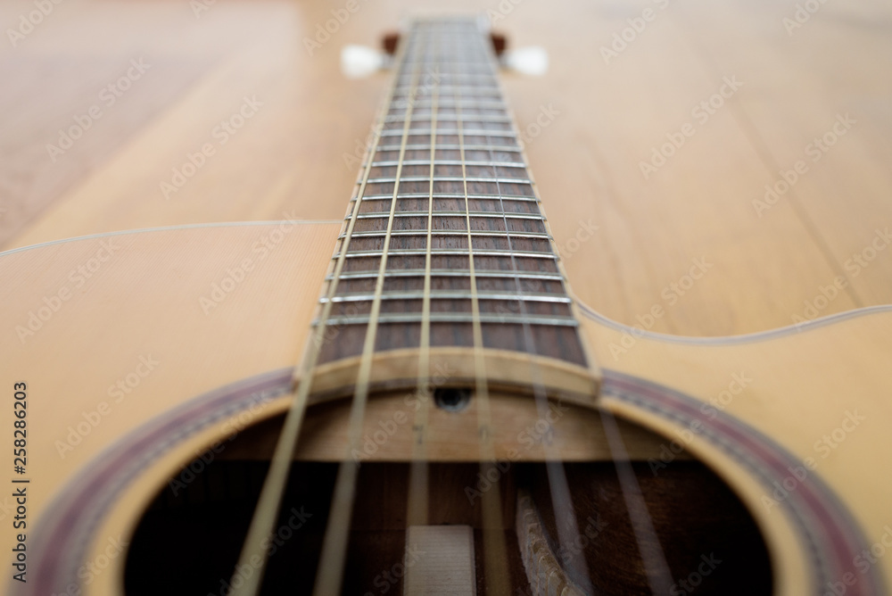 Guitar detail with part of body and neck, laying on a wooden floor