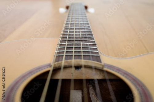Guitar detail with part of body and neck, laying on a wooden floor