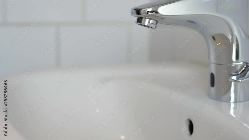 Man getting a glass of water from a touchless faucet Man getting a glass of water from a touchless faucet