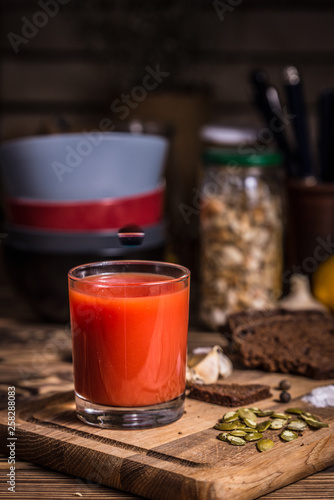 A glass of tomato juice on a wooden board with rye bread