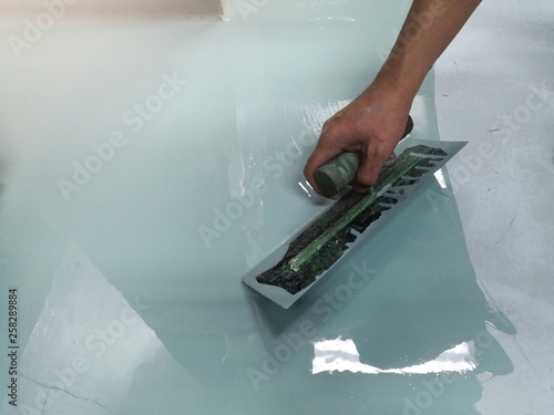 Construction workers are painting the floor using the method self-leveling epoxy.spreading self leveling compound with trowel.Self-leveling epoxy. Leveling with a mixture of cement floors. photo