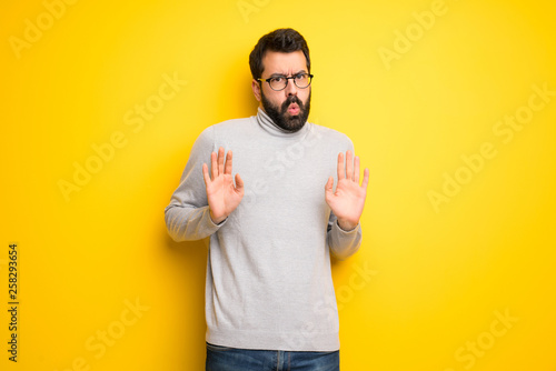 Man with beard and turtleneck making stop gesture with both hands