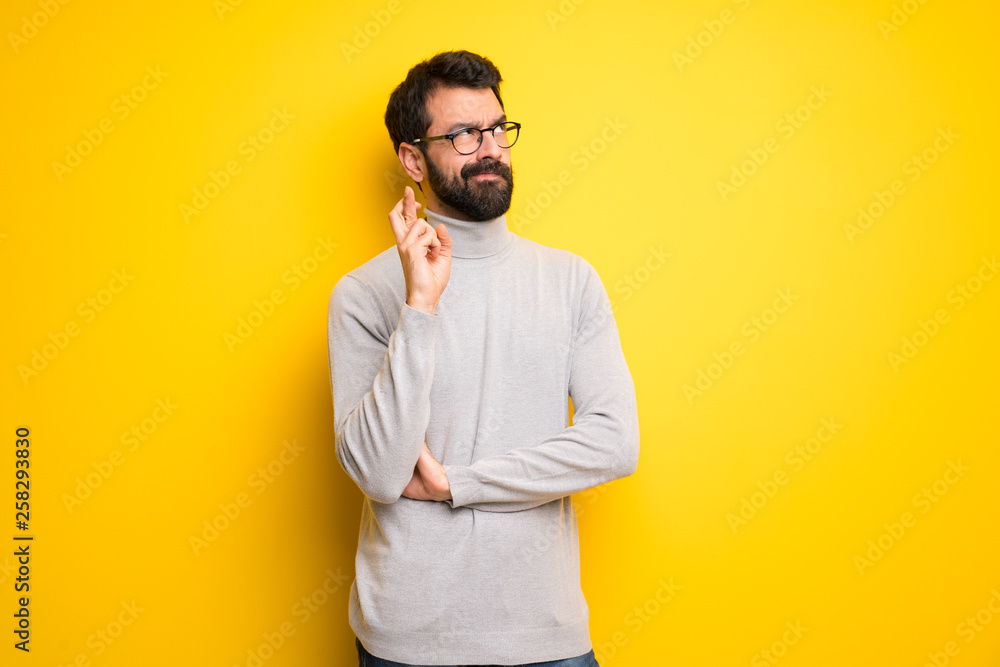 Man with beard and turtleneck with fingers crossing and wishing the best Man with beard and turtleneck with fingers crossing and wishing the best