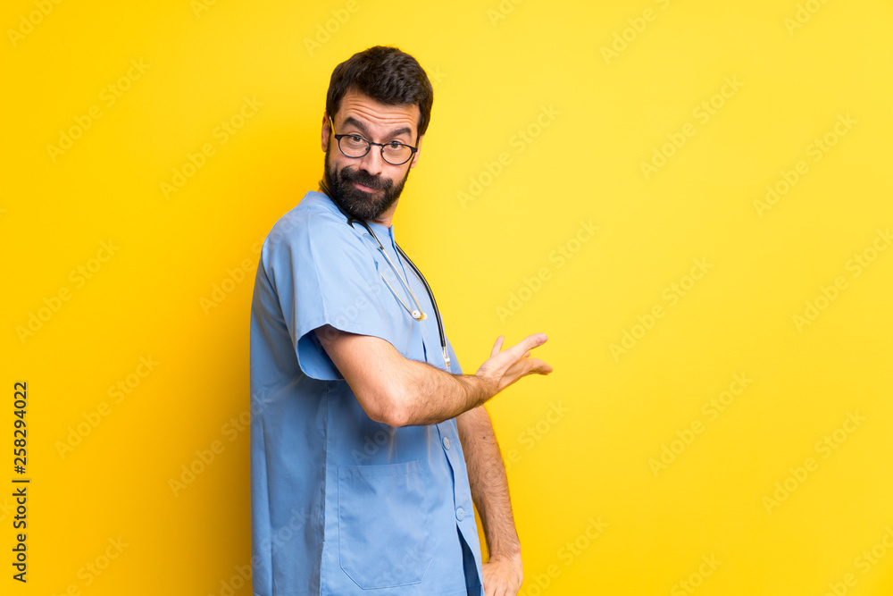 Surgeon doctor man pointing back and presenting a product Surgeon doctor man pointing back and presenting a product
