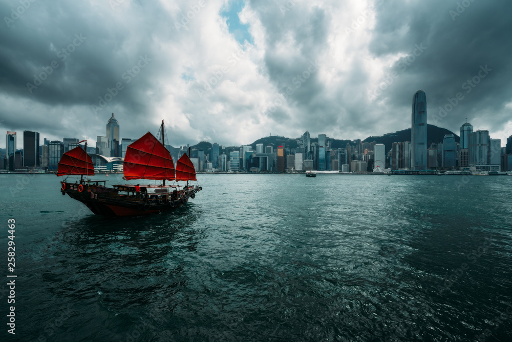 Naklejka premium Hong Kong City skyline with tourist sailboat. View from across Victoria Harbor Hong Kong.