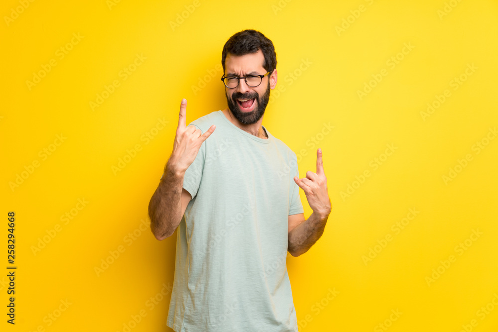Man with beard and green shirt making rock gesture Man with beard and green shirt making rock gesture
