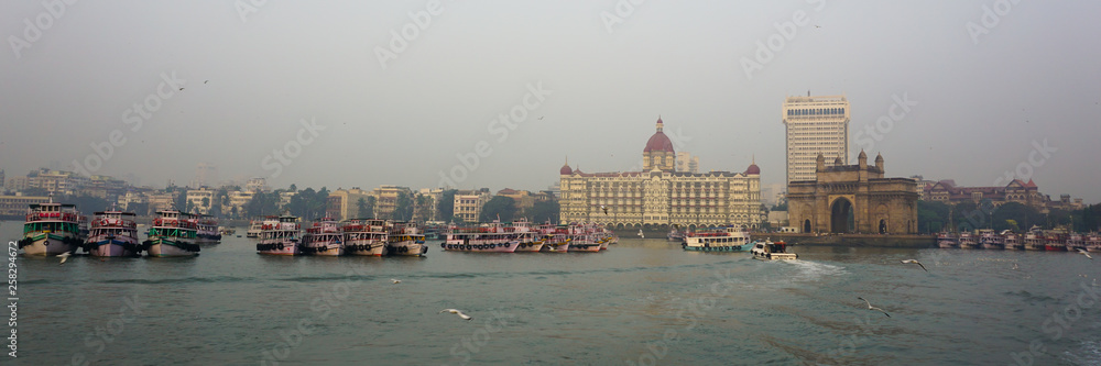 Mumbai city skyline in the evening taken from joy boat ride in the Arabian sea and iconic gateway of india and Taj Mahal hotel in view 