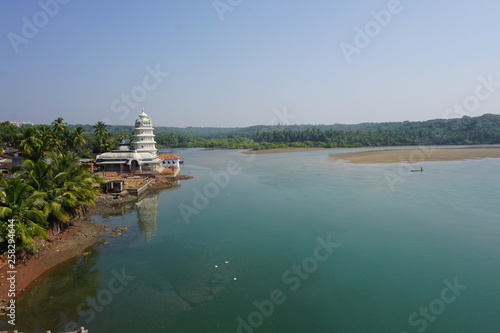 Fototapeta Naklejka Na Ścianę i Meble -  A white hindu temple on river bank in Kokan, Maharashtra, India. A scene in traditional village in India