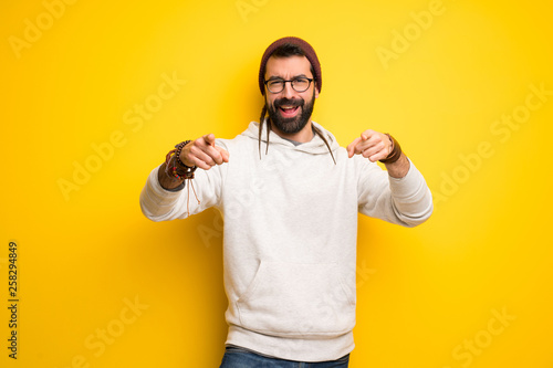 Hippie man with dreadlocks points finger at you while smiling