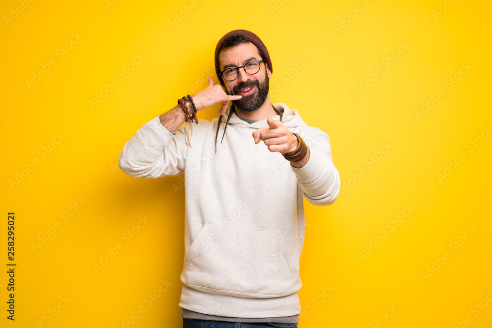 Hippie man with dreadlocks making phone gesture and pointing front Hippie man with dreadlocks making phone gesture and pointing front