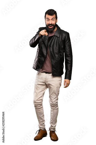 Handsome man with beard surprised and pointing front over isolated white background