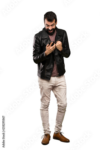 Handsome man with beard surprised and sending a message over isolated white background