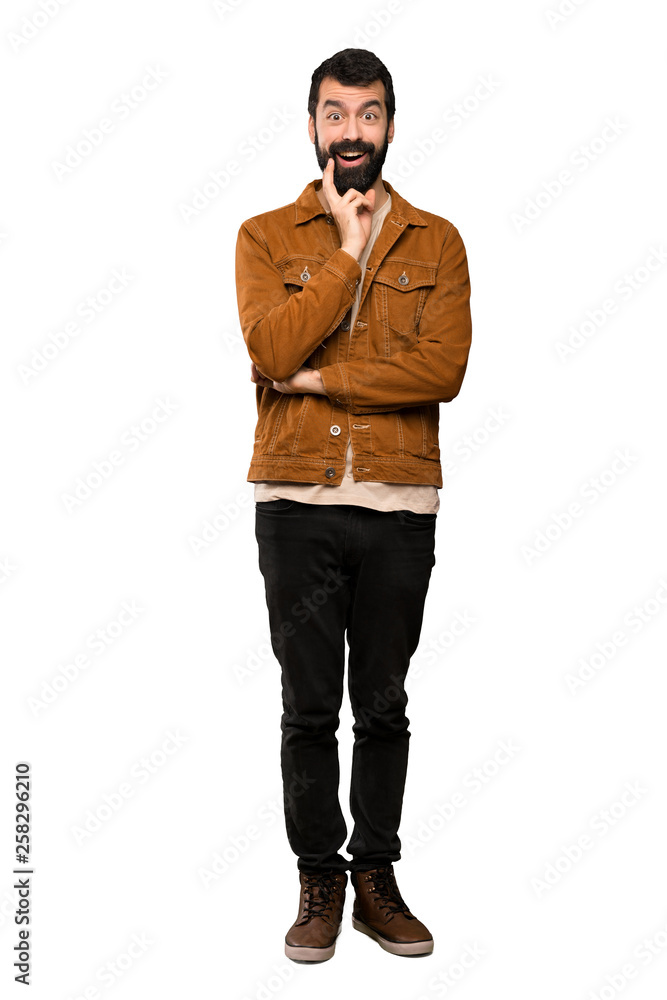 Handsome man with beard surprised and shocked while looking right over isolated white background Handsome man with beard surprised and shocked while looking right over isolated white background