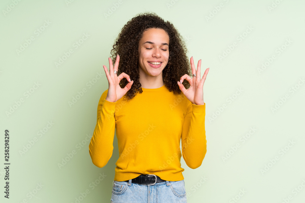 Dominican woman over isolated green background in zen pose Dominican woman over isolated green background in zen pose