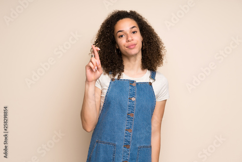 Dominican woman with overalls with fingers crossing and wishing the best