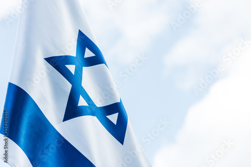 national flag of israel with blue star of david against sky with clouds photo
