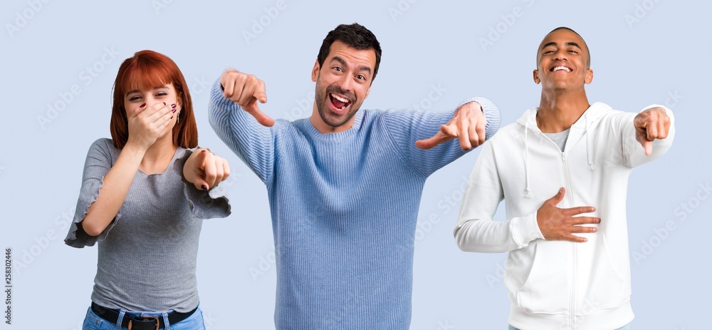 Group of three friends pointing with finger at someone and laughing a lot