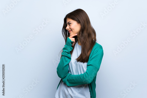 Teenager girl over blue wall looking to the side