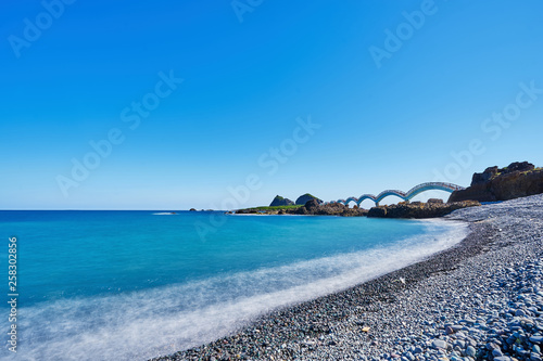 Beautiful scenic of Sanxiantai arch bridge with blue ocean with Three saint island in behind at Chenggong district in Taitung city, Taiwan. photo