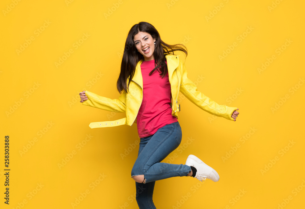 Teenager girl jumping over isolated yellow wall Teenager girl jumping over isolated yellow wall