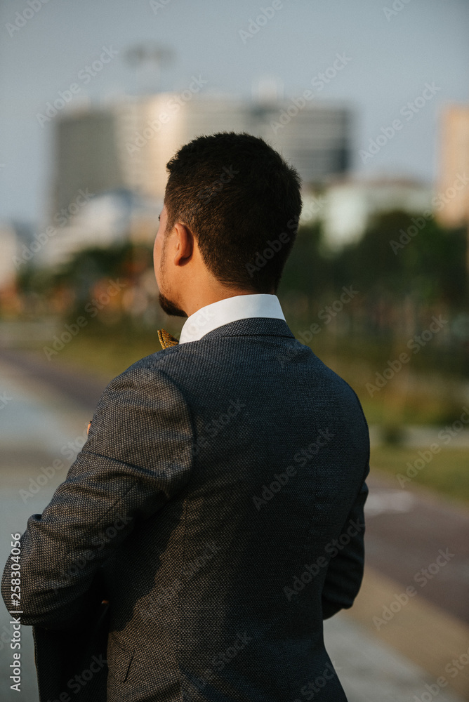 A man in a gray suit poses on the street to advertise men's clothing. Shooting for men's clothing store
