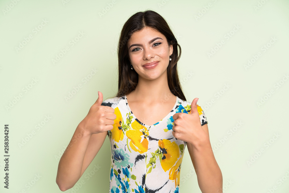 Teenager girl with floral dress giving a thumbs up gesture Teenager girl with floral dress giving a thumbs up gesture