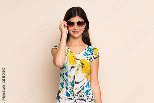 Teenager girl with floral dress with glasses and surprised © luismolinero