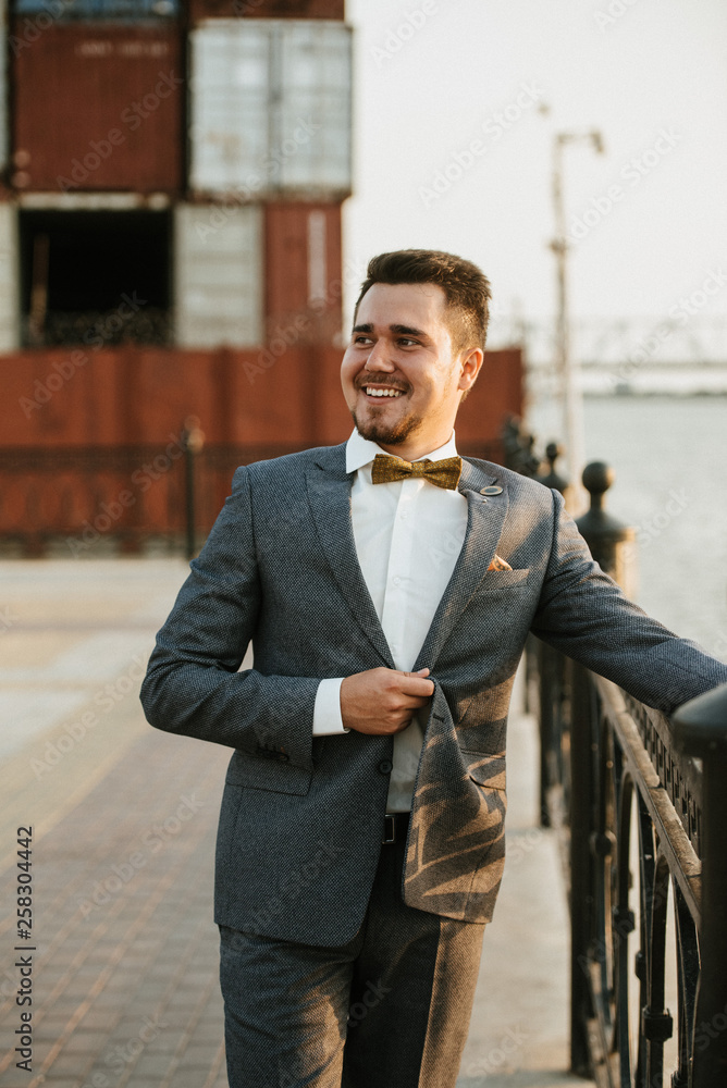 A man in a gray suit poses on the street to advertise men's clothing. Shooting for men's clothing store A man in a gray suit poses on the street to advertise men's clothing. Shooting for men's clothing store