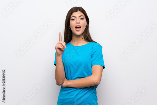 Teenager girl with blue shirt thinking an idea pointing the finger up