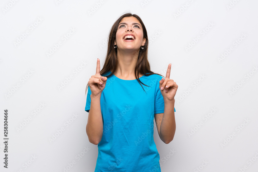 Teenager girl with blue shirt surprised and pointing up Teenager girl with blue shirt surprised and pointing up