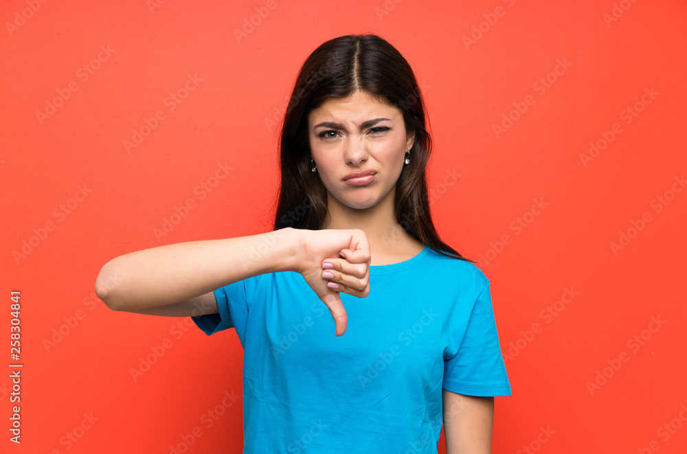 © luismolinero - Teenager girl with blue shirt showing thumb down sign