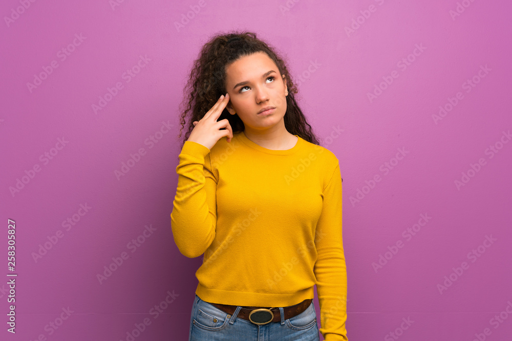 Teenager girl over purple wall with problems making suicide gesture Teenager girl over purple wall with problems making suicide gesture