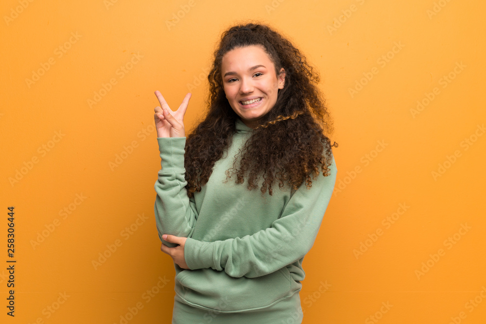 Teenager girl over ocher wall smiling and showing victory sign Teenager girl over ocher wall smiling and showing victory sign