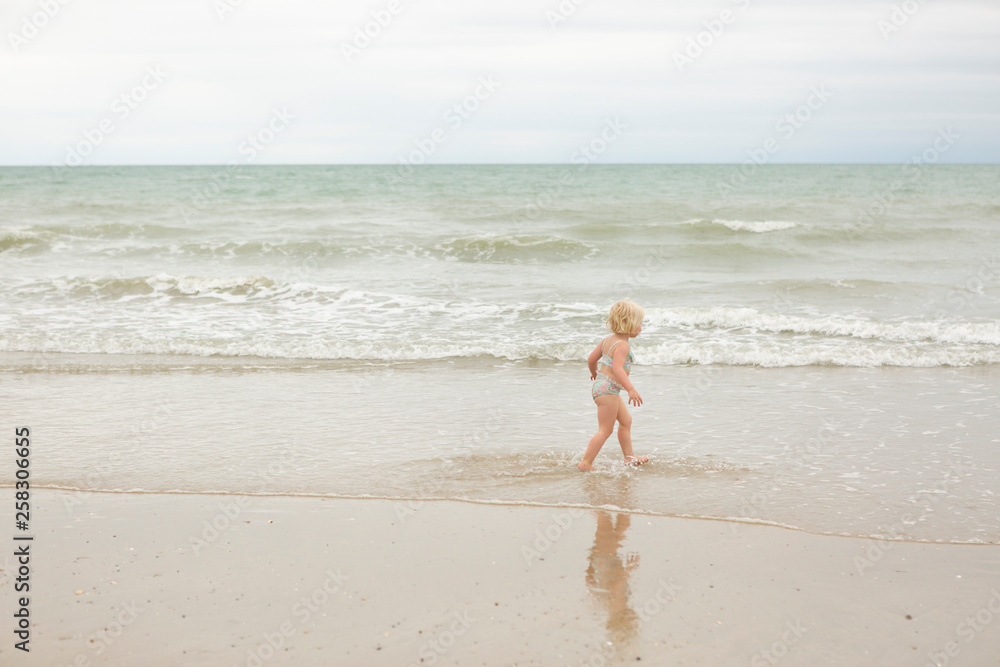 little girl running towards the waves