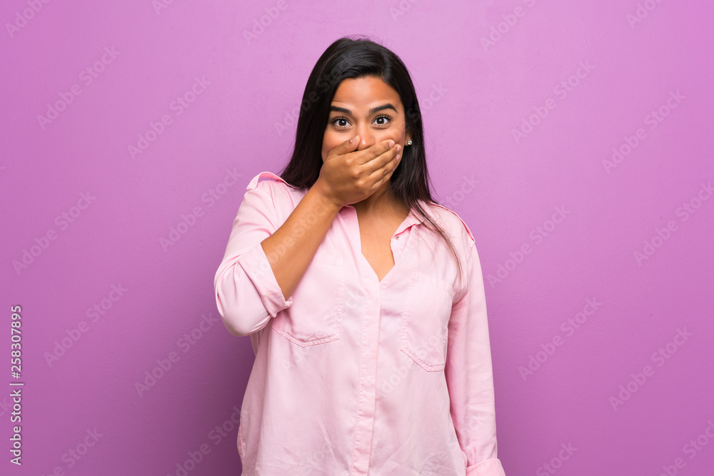 Young Colombian girl over purple wall covering mouth with hands Young Colombian girl over purple wall covering mouth with hands