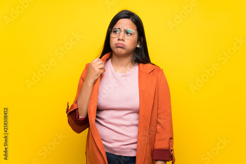 Young Colombian girl over yellow wall with tired and sick expression © luismolinero