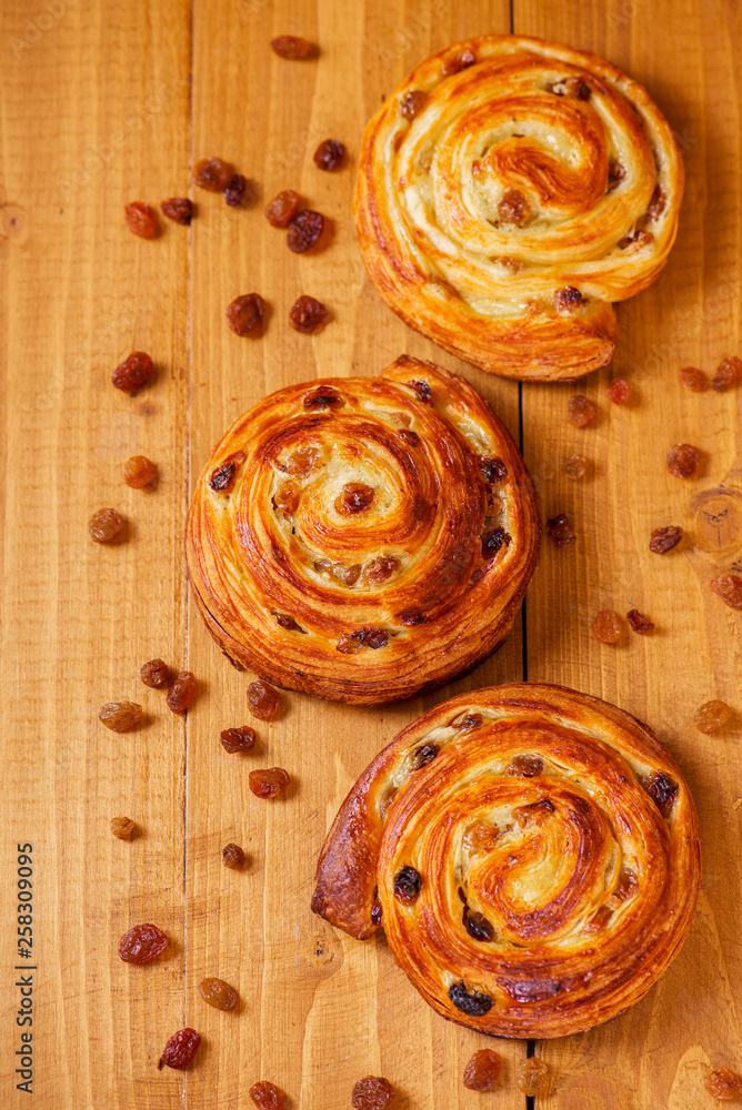 Fototapeta premium Fresh homemade pain au raisins croissant over wooden background