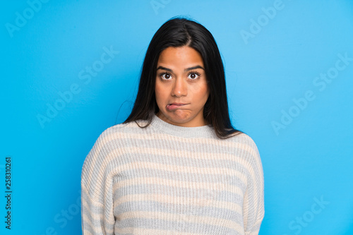 Young Colombian girl with sweater having doubts and with confuse face expression