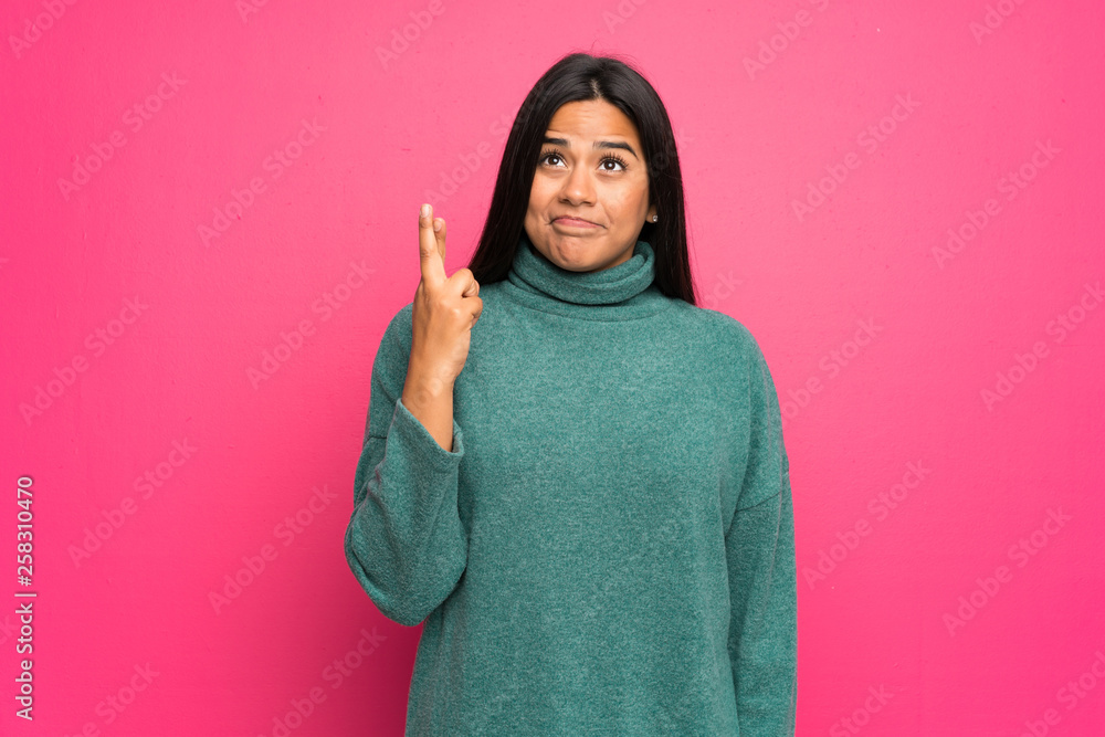 Young Colombian girl with green sweater with fingers crossing and wishing the best Young Colombian girl with green sweater with fingers crossing and wishing the best