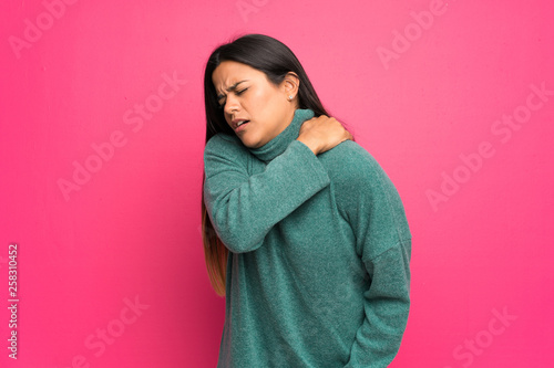 Young Colombian girl with green sweater suffering from pain in shoulder for having made an effort © luismolinero