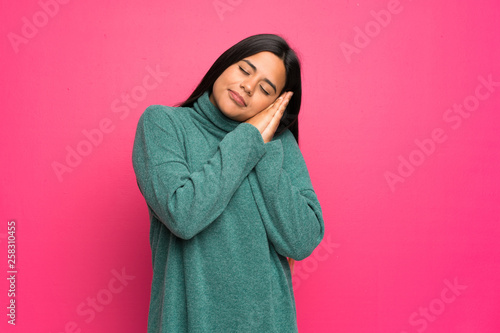 Young Colombian girl with green sweater making sleep gesture in dorable expression © luismolinero