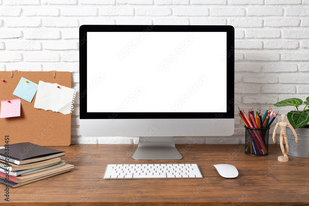 workspace with computer with blank white screen, and office supplies on a wooden desk workspace with computer with blank white screen, and office supplies on a wooden desk