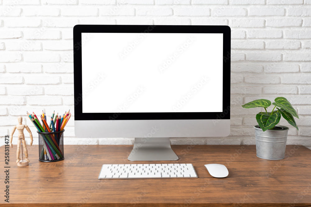 workspace with computer with blank white screen, and office supplies on a wooden desk workspace with computer with blank white screen, and office supplies on a wooden desk