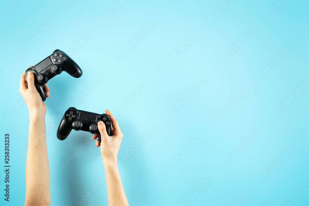 Fototapeta premium Two black joystick in hands isolated on pastel blue background