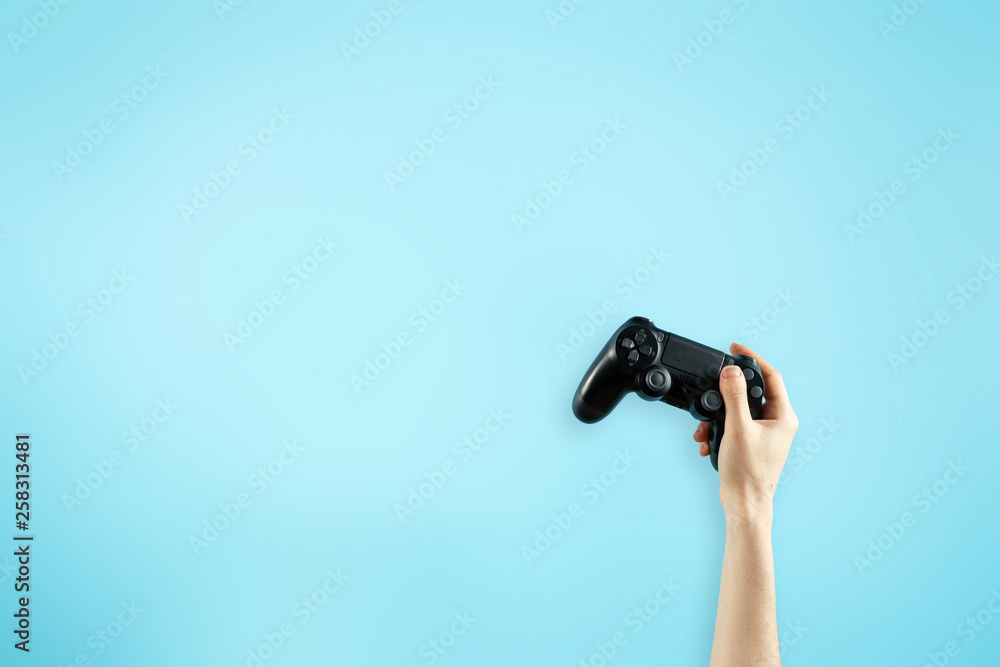 Black joystick in hands isolated on bright blue backg Black joystick in hands isolated on bright blue backg