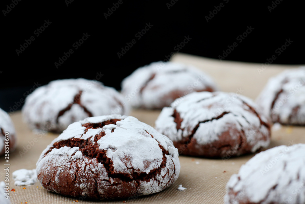 Chocolate cookies with cracks on baking paper and iolated on black. Cracked chocolate biscuits