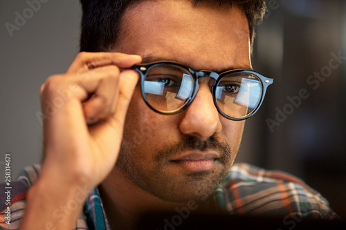 education, deadline and people concept - close up of creative man in glasses working at night office and thinking